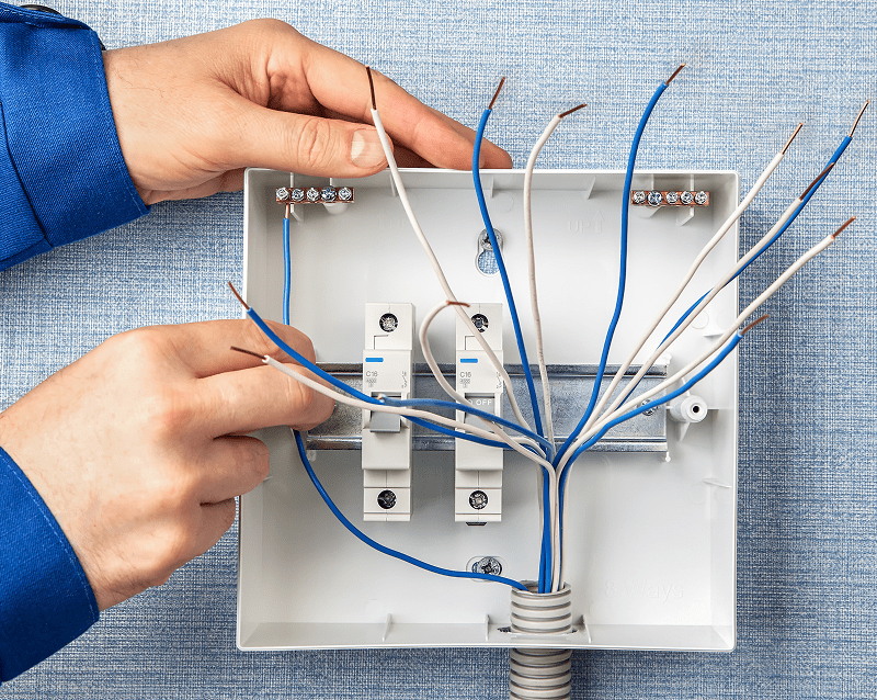 Hands working on electrical wiring box.