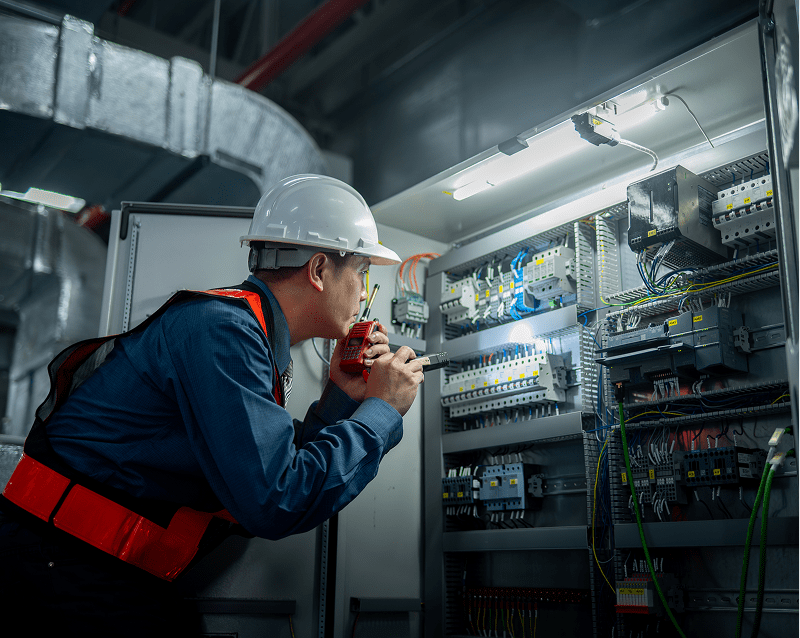 Electrician inspecting electrical panel with flashlight.