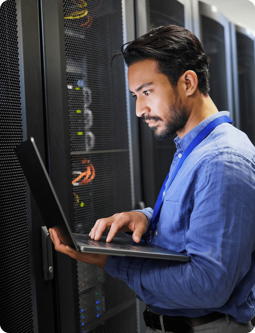 IT technician working on laptop in server room