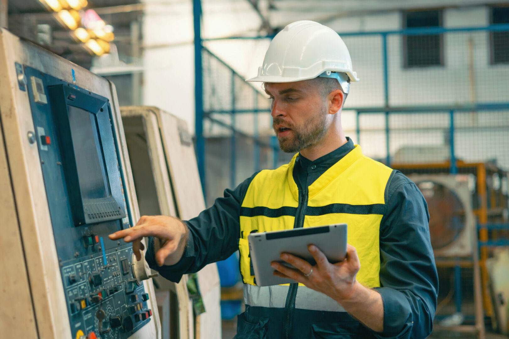 Factory technician using control panel and tablet